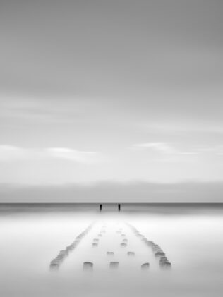 Wooden breakwater poles near Westkapelle gradually disappearing in the North Sea, in black & white. Vanishing - Copyright 2024 Johan Peijnenburg - NiO Photography