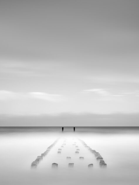 Wooden breakwater poles near Westkapelle gradually disappearing in the North Sea, in black & white. Vanishing - Copyright 2024 Johan Peijnenburg - NiO Photography