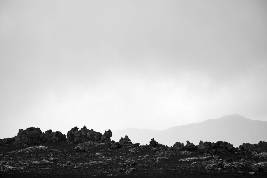 A misty and Icelandic landscape in B&W, featuring rugged lava stone and black sand and the mountains of Landmannalaugar. Rugged - Copyright 2022 Johan Peijnenburg - NiO Photography