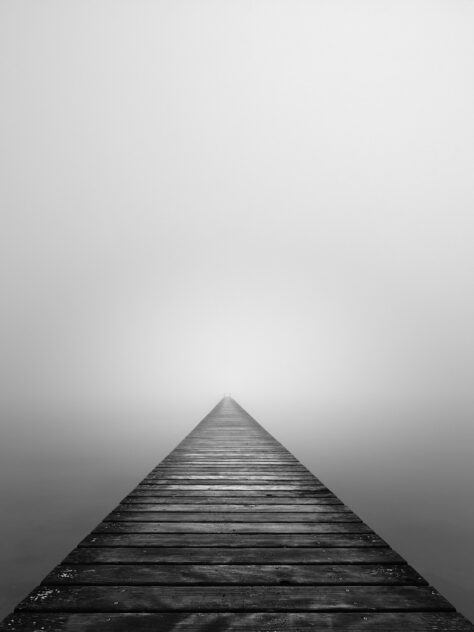 An old wooden pier disappearing into the mist above Lac de Neuchâtel in Switzerland, in black & white. The Abyss - Copyright 2022 Johan Peijnenburg - NiO Photography