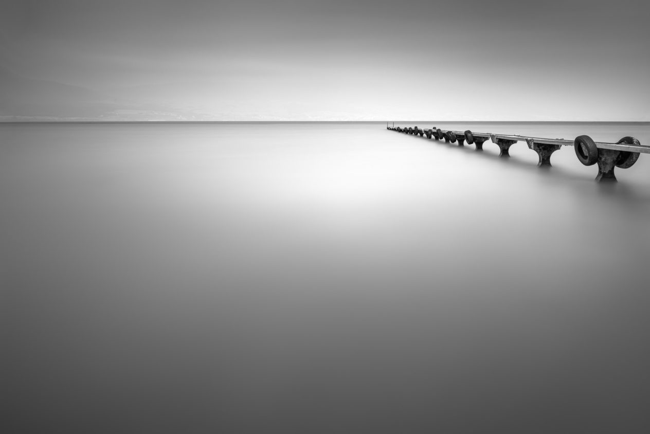 A lake landscape in  B&W, featuring an old abandoned pier in a lake on a mystical  foggy day (Lac de Neuchâtel in Switzerland). Abandoned - Copyright Johan Peijnenburg - NiO Photography