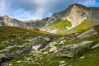 A rocky alpine meadow and the mountains of the Italian Alps (Pointe de Drône) catching first morning light just after sunrise. Early Ascent - Copyright Johan Peijnenburg - NiO Photography