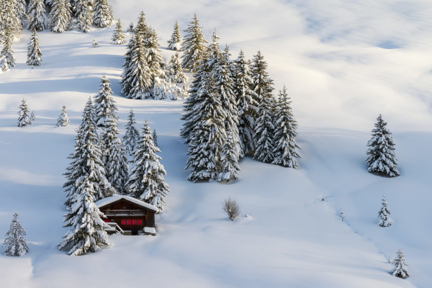 A Swiss winter landscape, featuring a chalet and trees on a mountain slope with virgin snow in the Swiss Alps at sunset. Swiss Winter - Copyright Johan Peijnenburg - NiO Photography