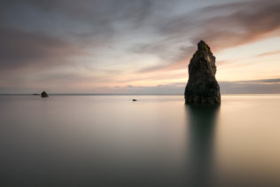 A coastal landscape ahowing a colourful sunset at the Ballydowane Cove sea stack and the North Atlantic Ocean in County Waterford, Ireland. Calming - Copyright Johan Peijnenburg - NiO Photography