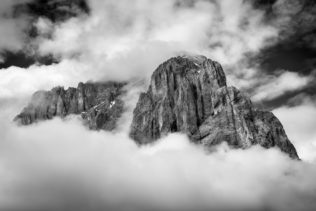 A mountain landscape in B&W, featuring Sassolungo (Langkofel) in the Dolomites of South Tyrol in Italy enclosed by clouds and fog. Dramatic - Copyright Johan Peijnenburg - NiO Photography