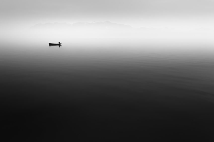 A fisherman at work on his boat on a misty Lac Léman (Lake Geneva) in Switzerland with the French Alps in the background. A Day at the Office - Copyright Johan Peijnenburg - NiO Photography