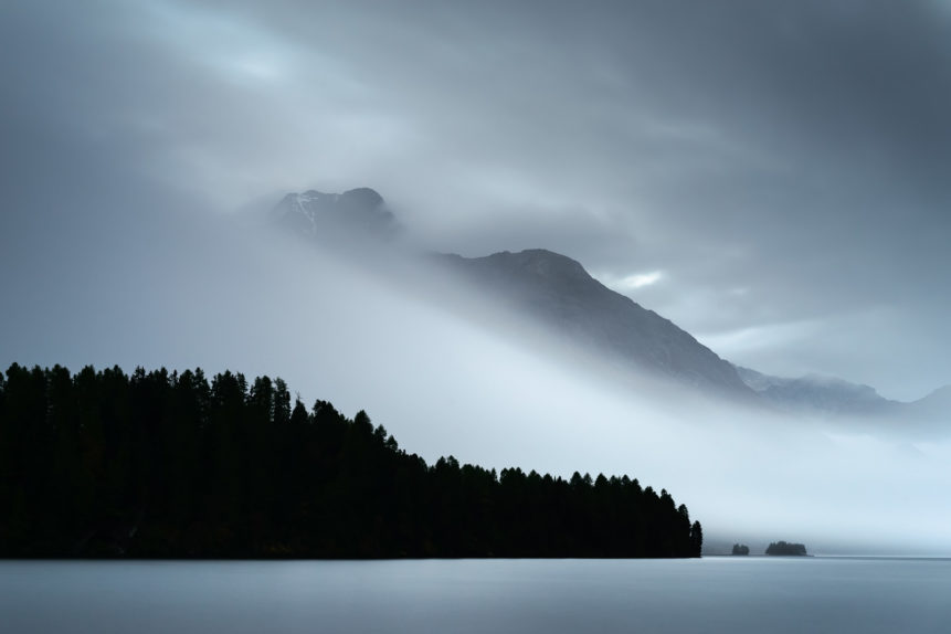 A lake landscape, showing Piz de la Margna with magical light and a fog phenomenon called the Maloja Snake at Lake Sils in Switzerland. Engulfed - Copyright Johan Peijnenburg - NiO Photography