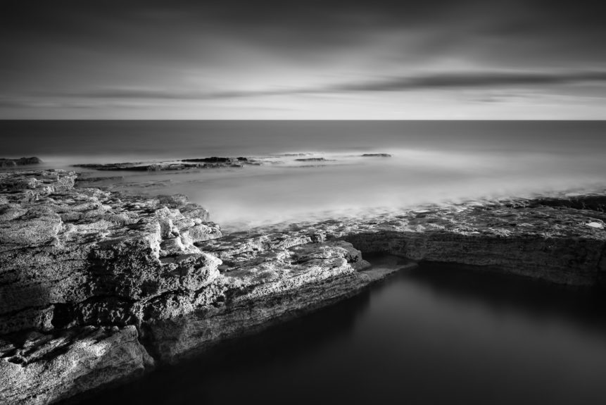 A black & white coastal landscape featuring the rock formations of the rugged Irish coast near Hook Head in County Wexford at sunset. Force of Nature - Copyright Johan Peijnenburg - NiO Photography