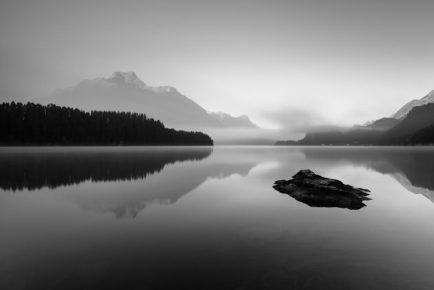 A sunrise with the reflections of mountains and a larch tree forest in Lake Sils (Silsersee, Lej da Segl), a mountain lake in the Alps. Enjoy the Silence - Copyright 2016 Johan Peijnenburg