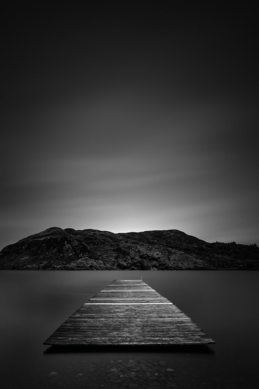 An Irish lake landscape in black & white, featuring a pier in Lough Caragh and the hills of Killarney National Park in County Kerry, Ireland. Afloat - Copyright Johan Peijnenburg - NiO Photography