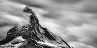 A mountain landscape in black & white, featuring the east and north faces of the iconic Matterhorn (Cervino) with snow, fog and clouds. Iconic - Copyright Johan Peijnenburg - NiO Photography