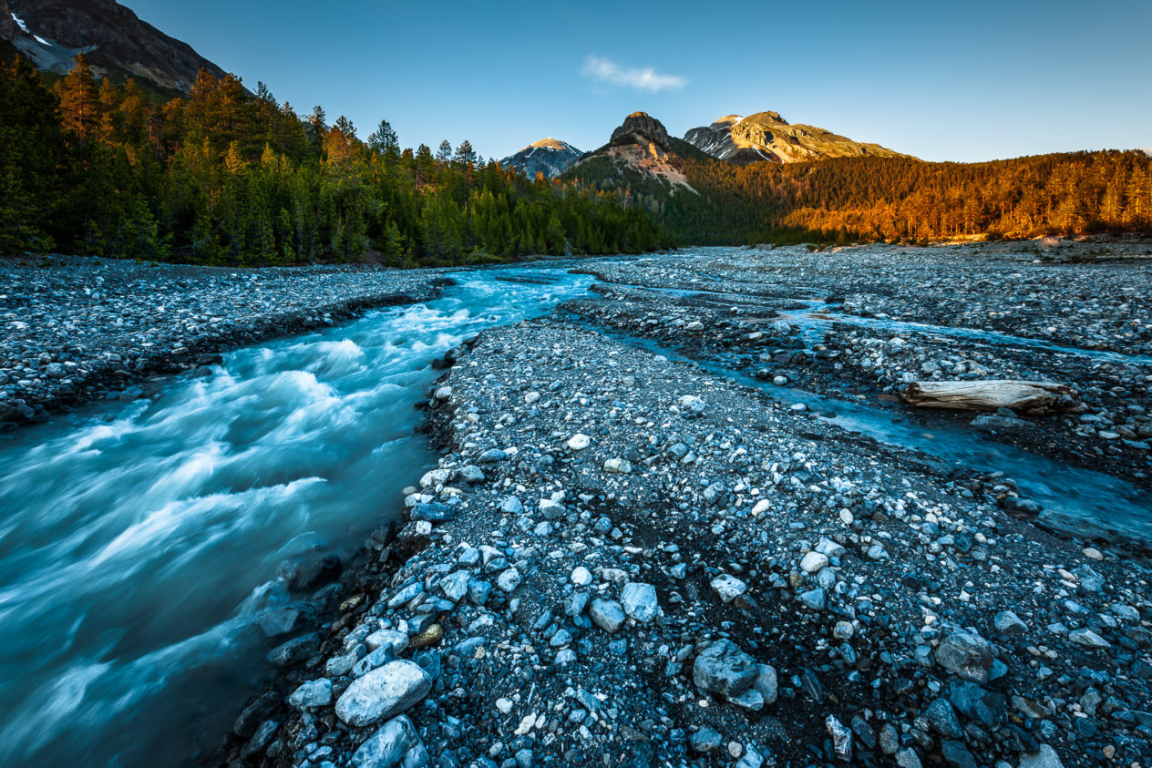 A mountain landscape, featuring an alpine mountain river in the Swiss National Park flowing down from the Alps at sunset. Alpine mountain river sunset - Copyright Johan Peijnenburg - NiO Photography