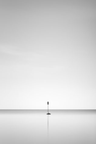 A minimalist landscape in black & white, featuring a solitary signpost and its reflection in Lac Léman (Lake Geneva). One - Copyright Johan Peijnenburg - NiO Photography