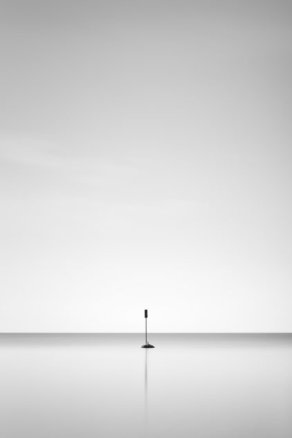 A minimalist landscape in black & white, featuring a solitary signpost and its reflection in Lac Léman (Lake Geneva). One - Copyright Johan Peijnenburg - NiO Photography