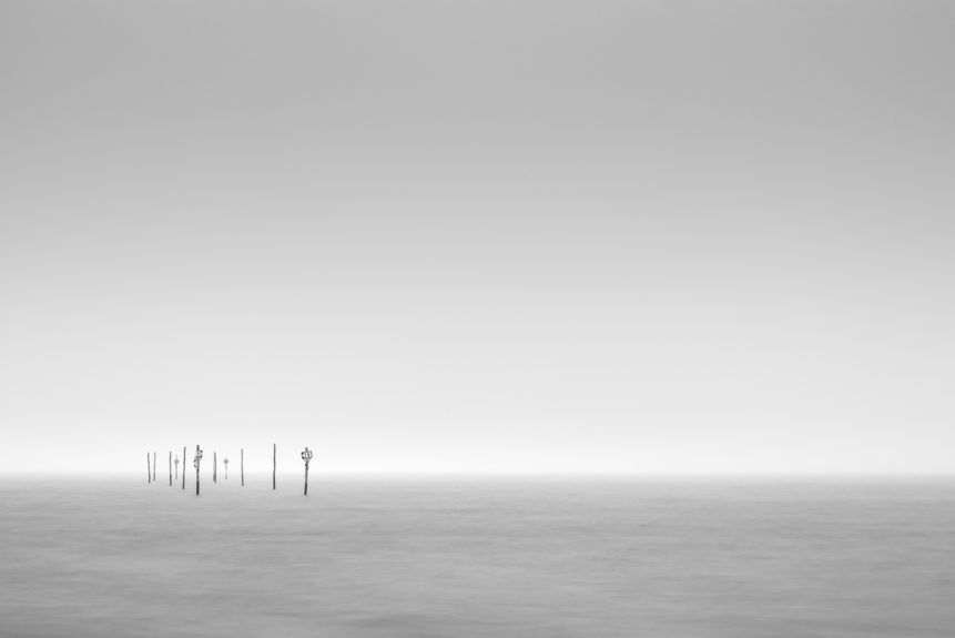 A minimalist Dutch coastal landscape in B&W with signposts at the coast of the Oosterschelde near Tholen in Zeeland on a foggy day. Passage - Copyright Johan Peijnenburg - NiO Photography