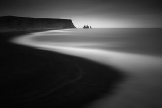 The black sand beach of Reynisfjara and the Reynisdrangar sea stacks near Vík í Mýrdal, Iceland, in black & white. Curved - Copyright Johan Peijnenburg - NiO Photography