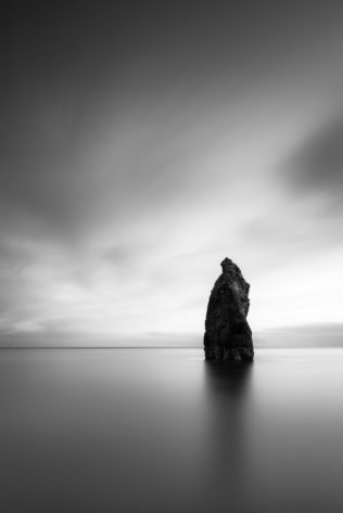 A minimalist Irish landscape in B&W, featuring a sea stack and the Celtic Sea at Ballydowane Cove in the Copper Coast Geopark, in County Waterford, Ireland. The Philosopher's Stone - Copyright Johan Peijnenburg - NiO Photography