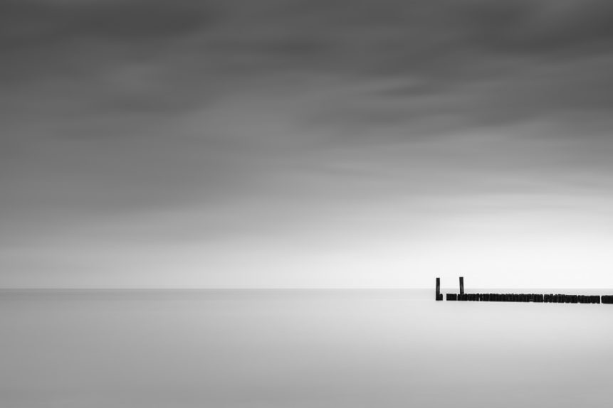 A minimalist coastal landscape in B&W with a dark sky above a breakwater in the North Sea near Domburg in Zeeland, The Netherlands. Ending silence - Copyright Johan Peijnenburg - NiO Photography